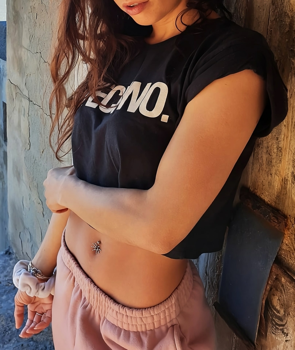 Beautiful woman wearing Techno Croptop, leaning against the wall, no face showing.