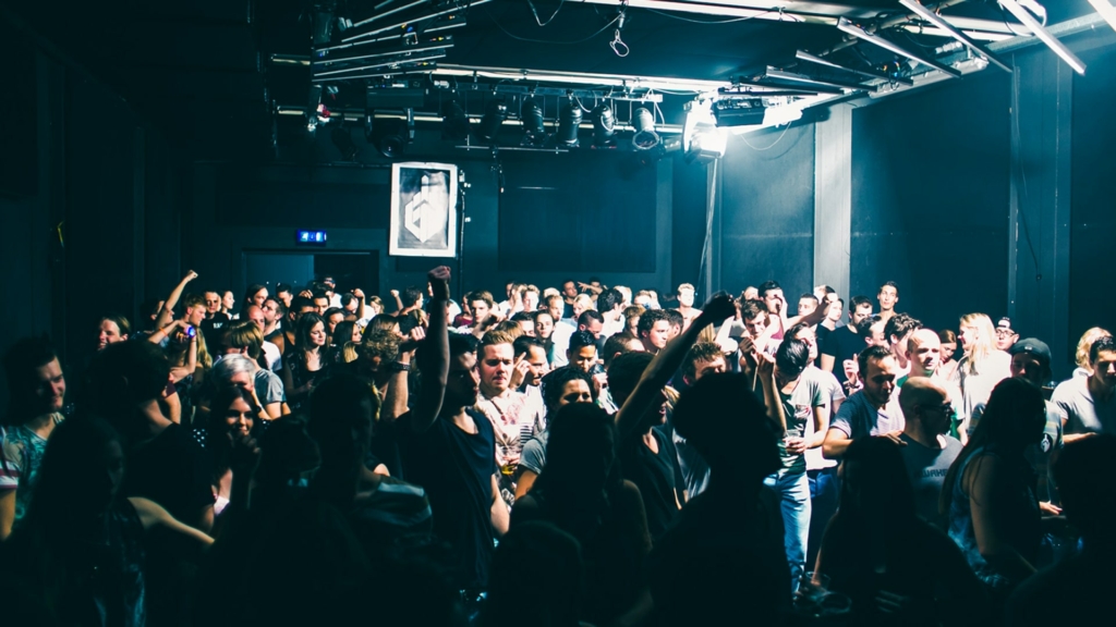 A euphoric crowd dances under flashing strobe lights in a dark club during a Fack It night in Tilburg.