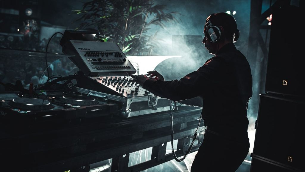 Jeff Mills, deeply focused, spinning records behind the decks during a high-energy techno performance.